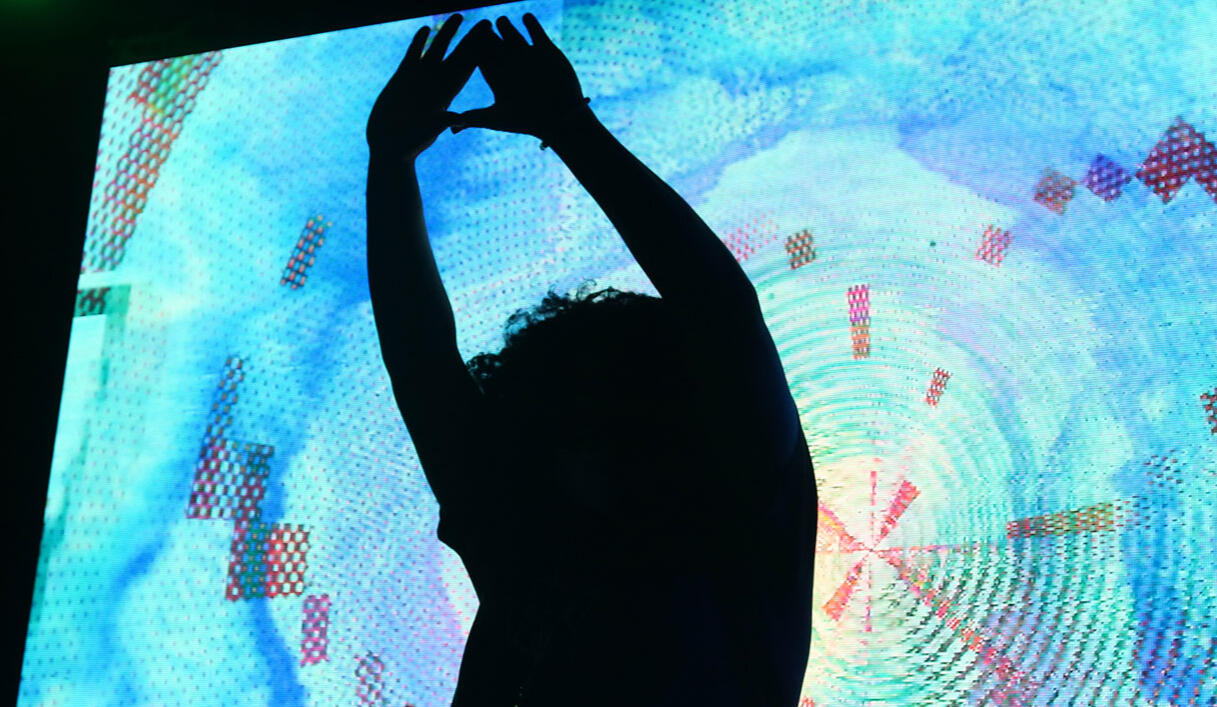 The silhouette of Dinaari stretching against a colorful backdrop